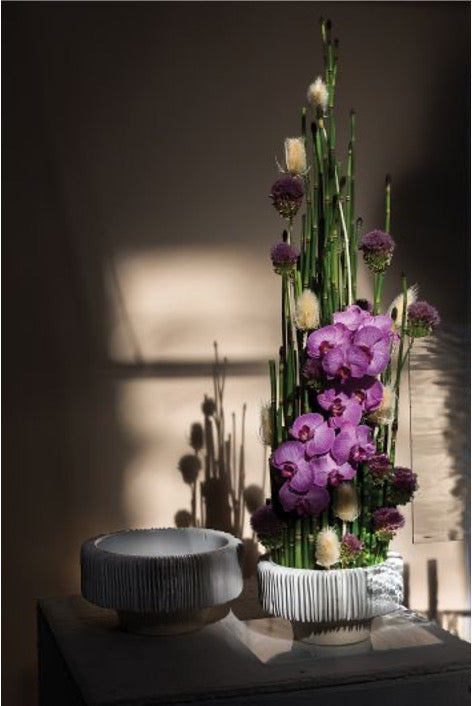 Set of white ceramic compotes with thin slices pattern.  Purple orchid and bamboo arrangement