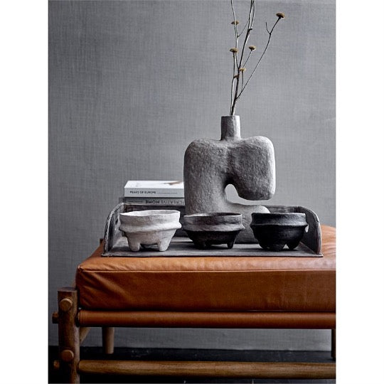 abstract vase in with dried flowers and rustic bowls on brown leather ottoman