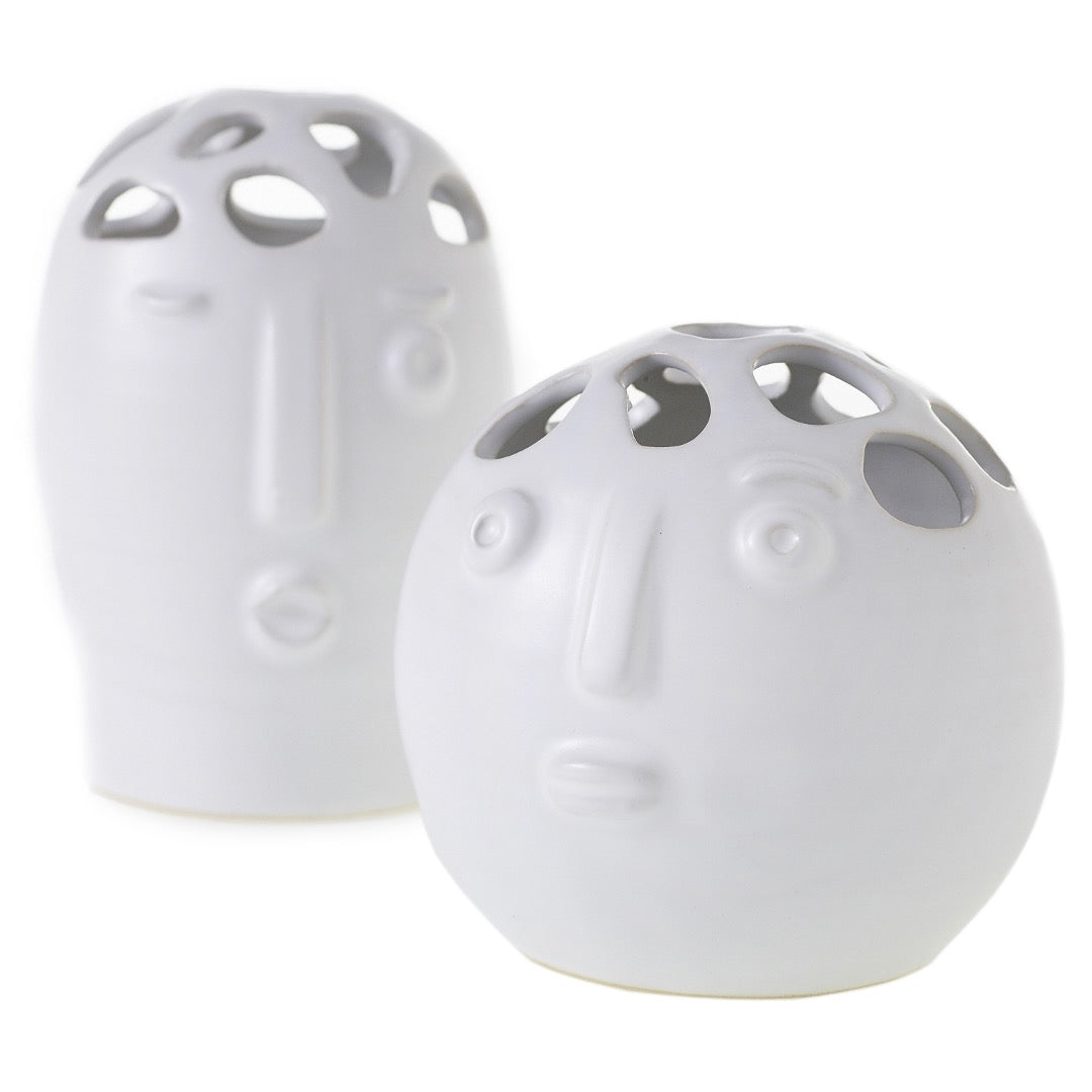Two matte white Picasso bud vases with sculpted faces and cutout tops, one tall oval and one round