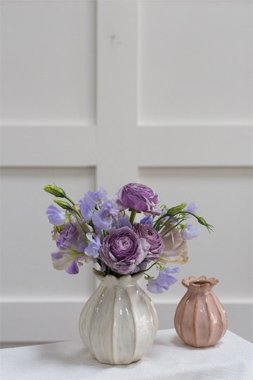 Tulip shaped ceramic budvase  set with violet flowers in background..