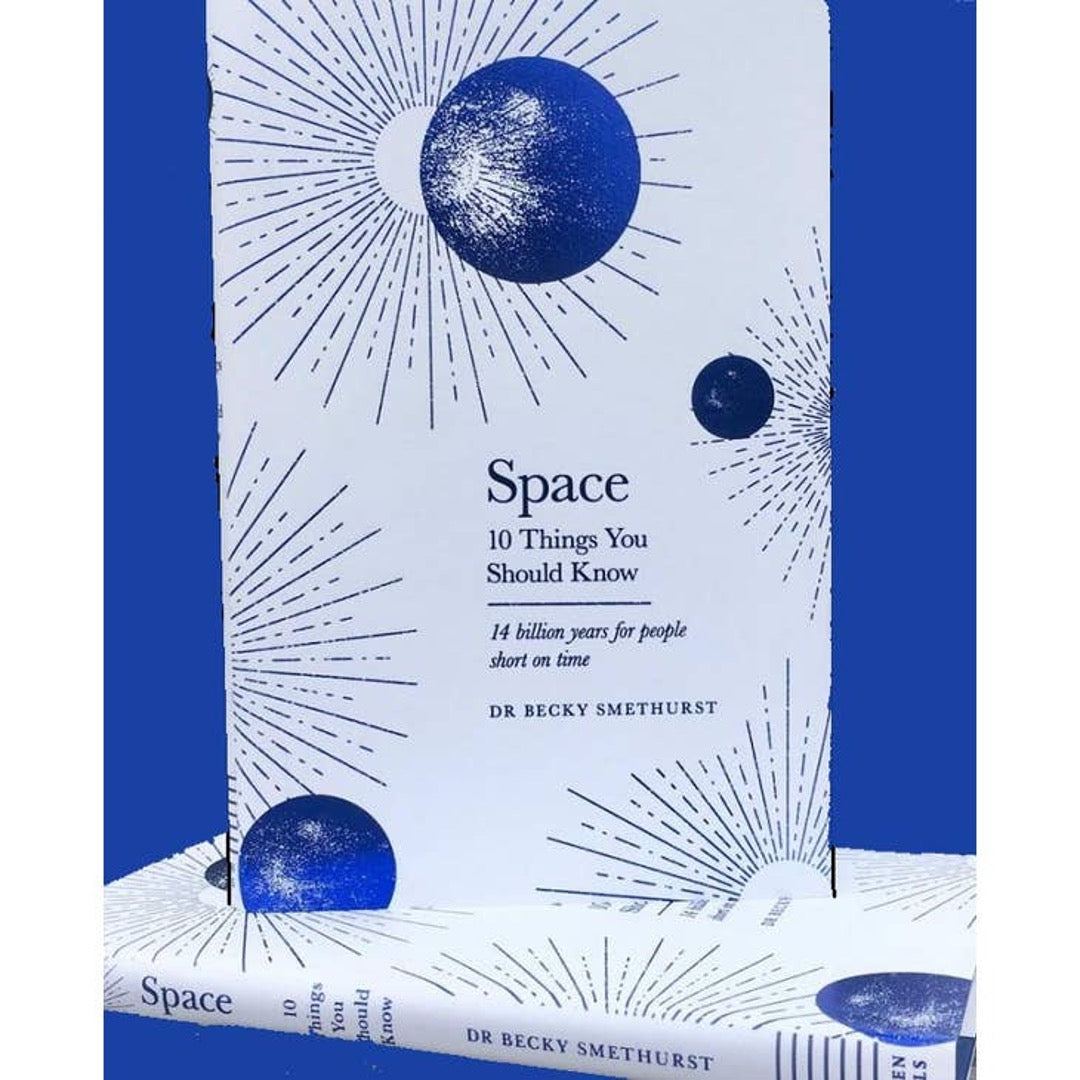 Space book standing on a second copy lying flat, against a bright blue background