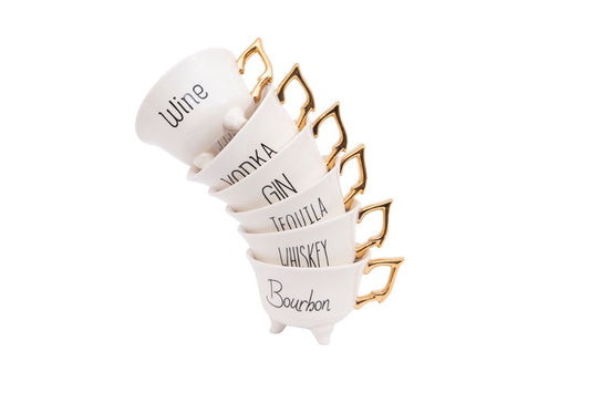 Six tea cups with gold handles stacked.  Each tea cup has black text with Wine, Vodka, Gin, Tequila, Whiskey, or Bourbon on side.